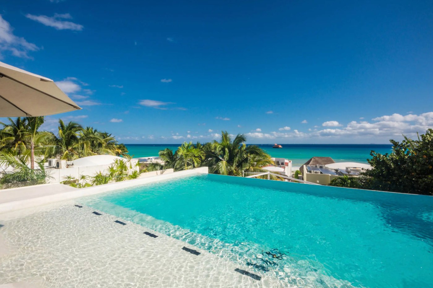 Alberca infinita en la azotea de una casa en Playacar Fase 1, con vista sobre las palmas al Caribe