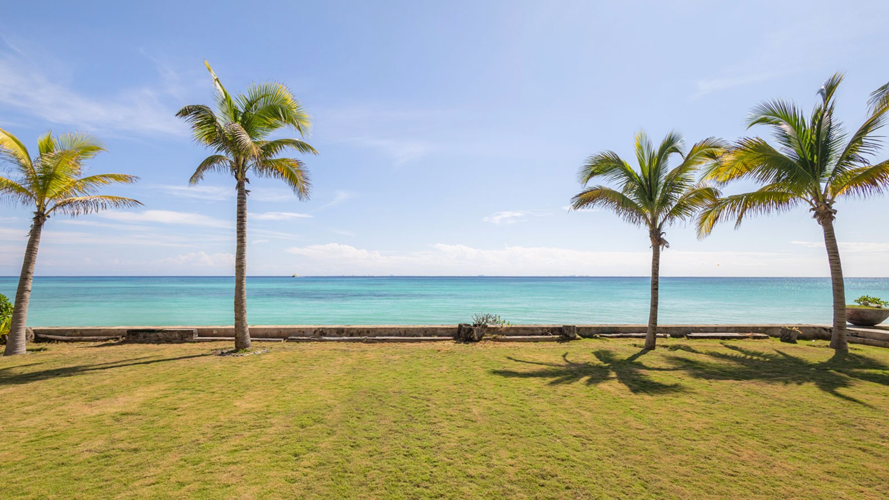 Jardín frente al mar con palmas y un muro bajo en Playacar Fase 1