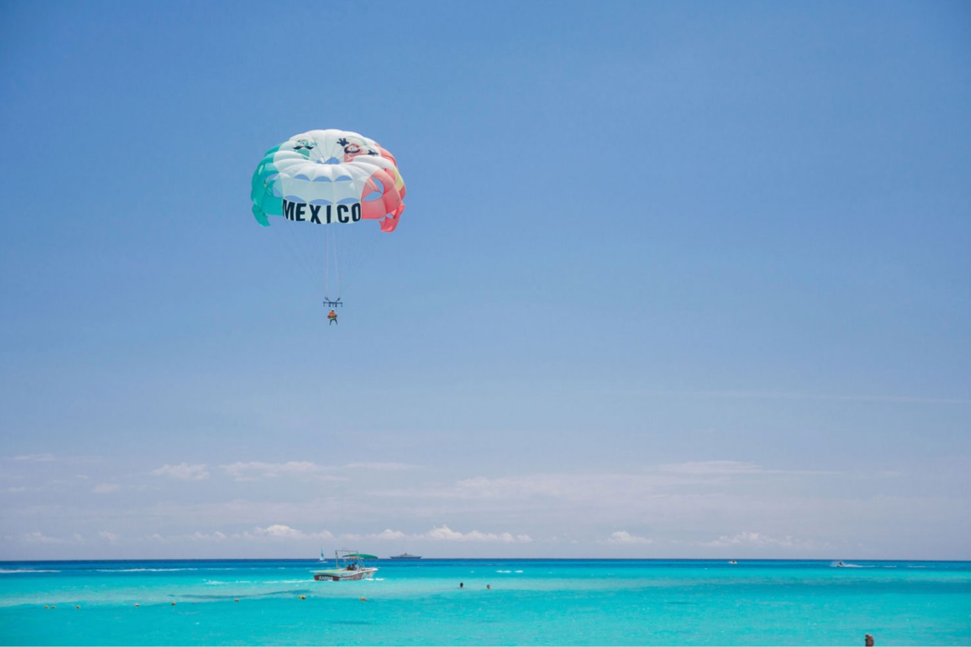 Parasail over clear turquoise water off the beach at Playacar