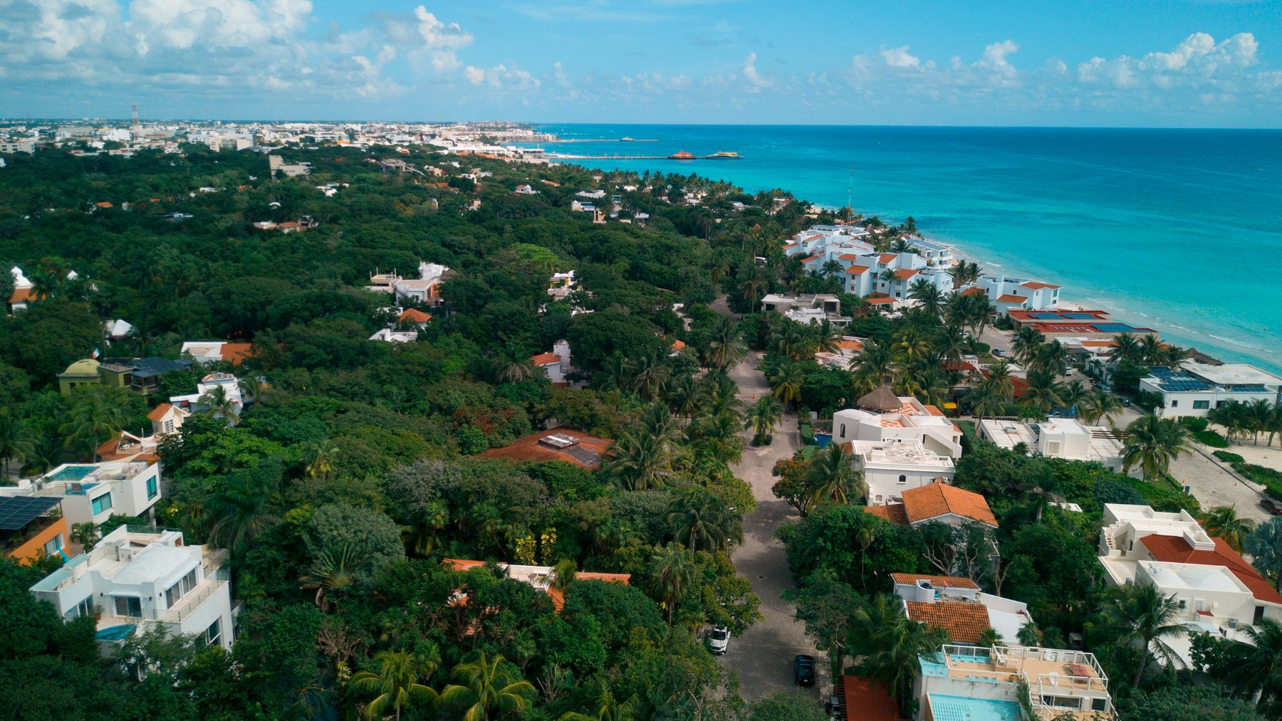 Aerial view of Playacar Fase 1 streets under canopy, with the ferry pier and Playa del Carmen beyond