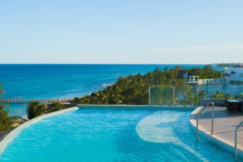 Alberca infinita en la azotea de MVNGATA con vista sobre las palmeras al arrecife y el mar abierto