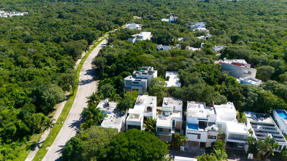 Vista aérea de Selvamar en Playa del Carmen, casas contemporáneas blancas con paneles solares en plena selva con el Caribe en el horizonte