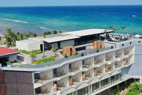 Aerial of the MVNGATA beach club building at Xcalacoco, curved white balconies facing the reef and the Caribbean