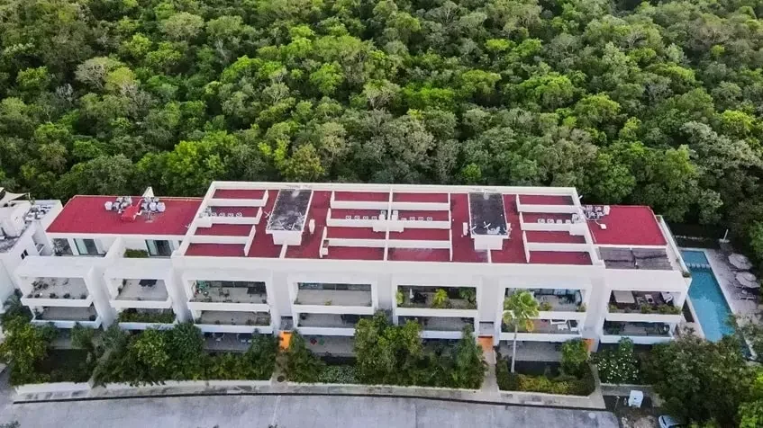 Aerial of a three storey condominium building in Selvamar with planted terraces, a pool at one end and jungle behind
