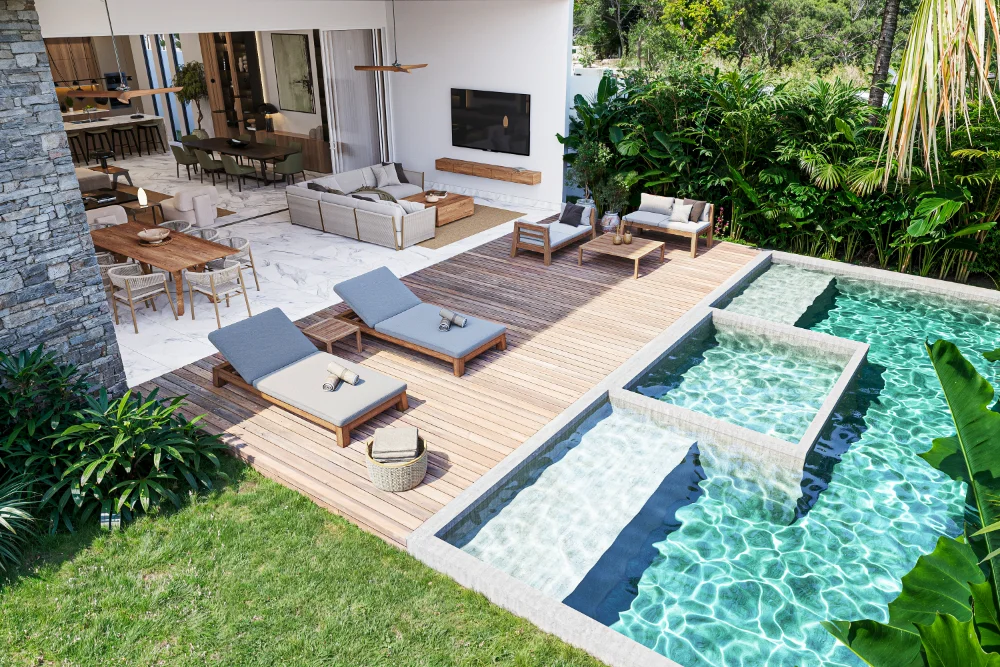 Piscine, terrasse en bois et séjour ouvert d'une villa à Selvamar, adossée à la jungle