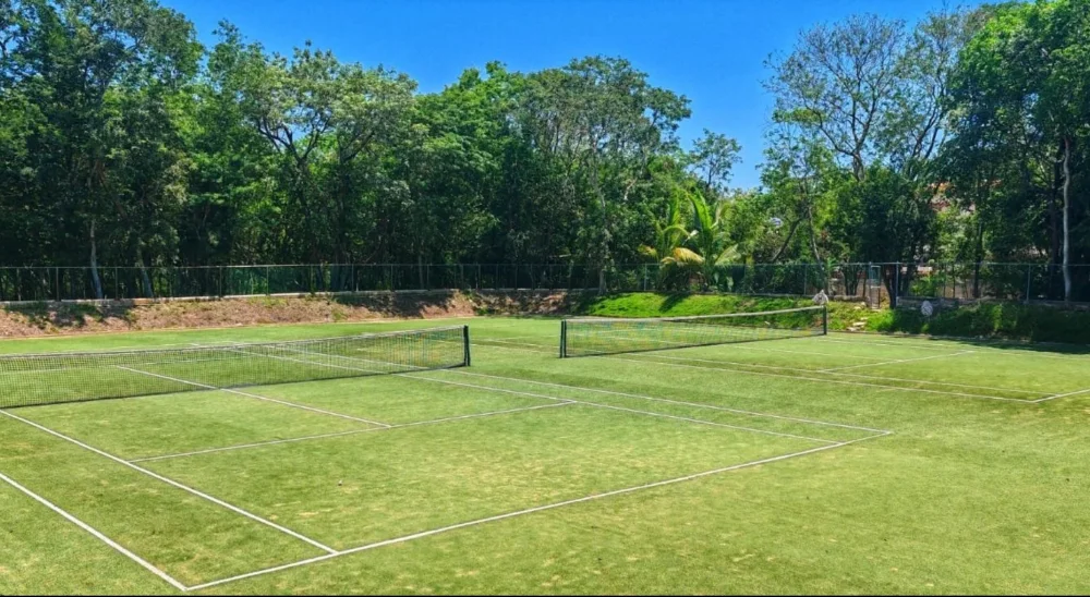 Deux courts de tennis sur gazon à Selvamar entourés de jungle sous un ciel bleu