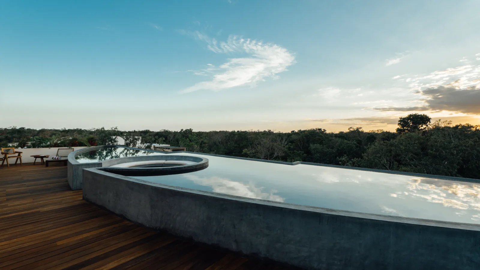 Piscine et terrasse sur le toit d'une villa de la Riviera Maya, chaises longues sous une palapa et jungle au fond