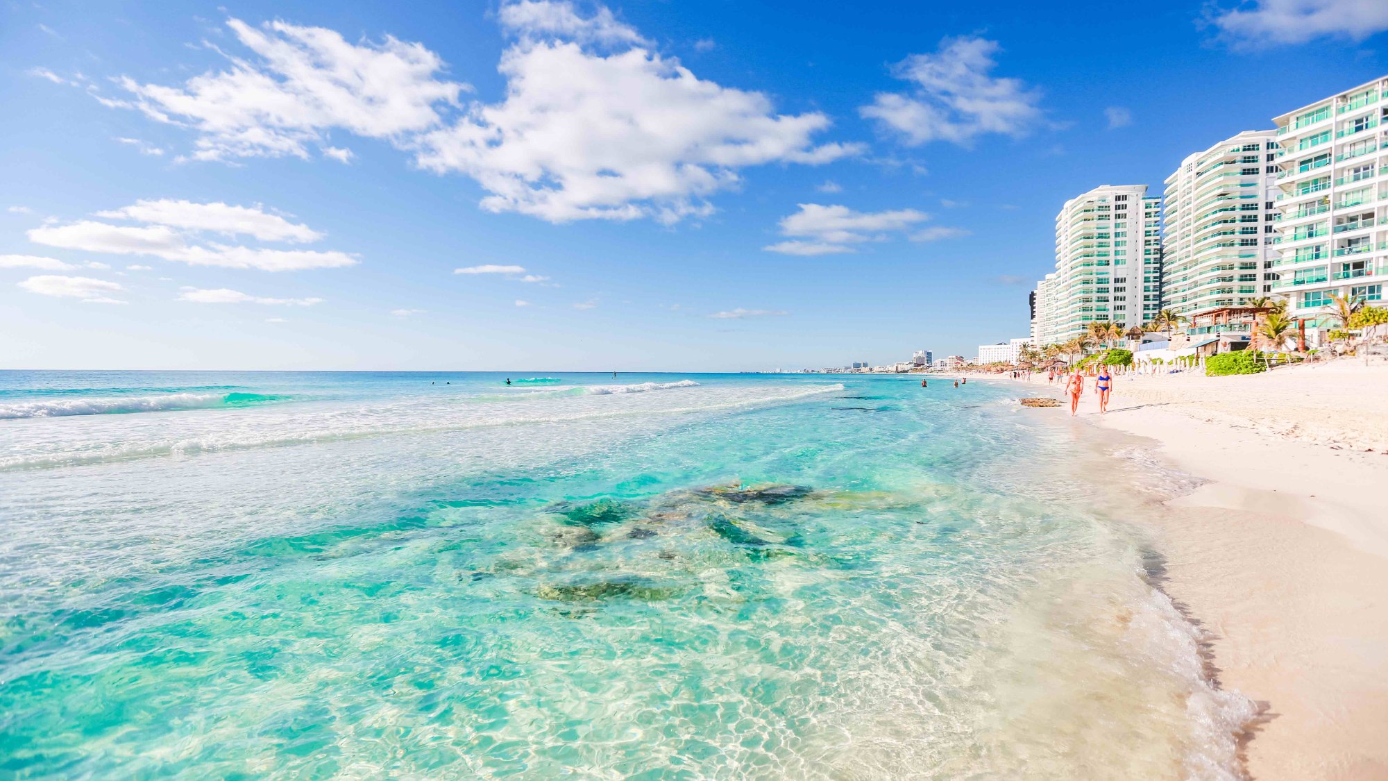 Clear shallow water and white sand in front of the beachfront condominium towers of the Cancún Hotel Zone