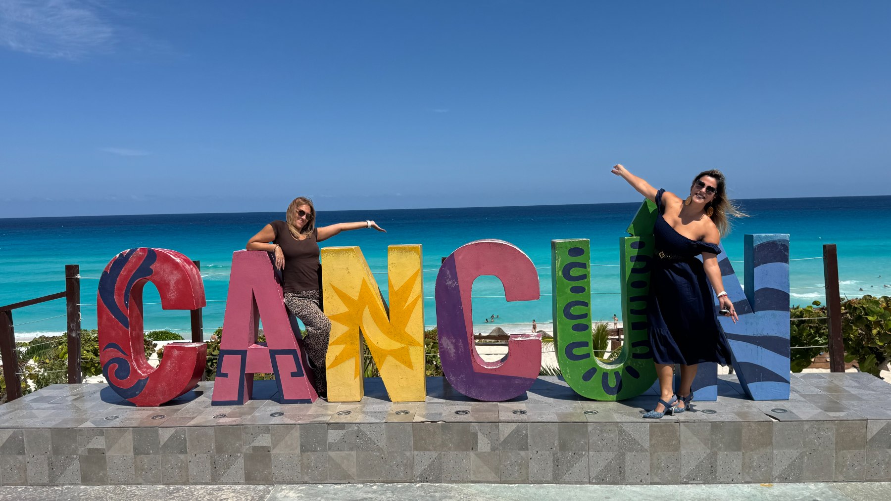 Visiteurs posant devant les lettres colorées de Cancún au-dessus de la plage à Playa Delfines