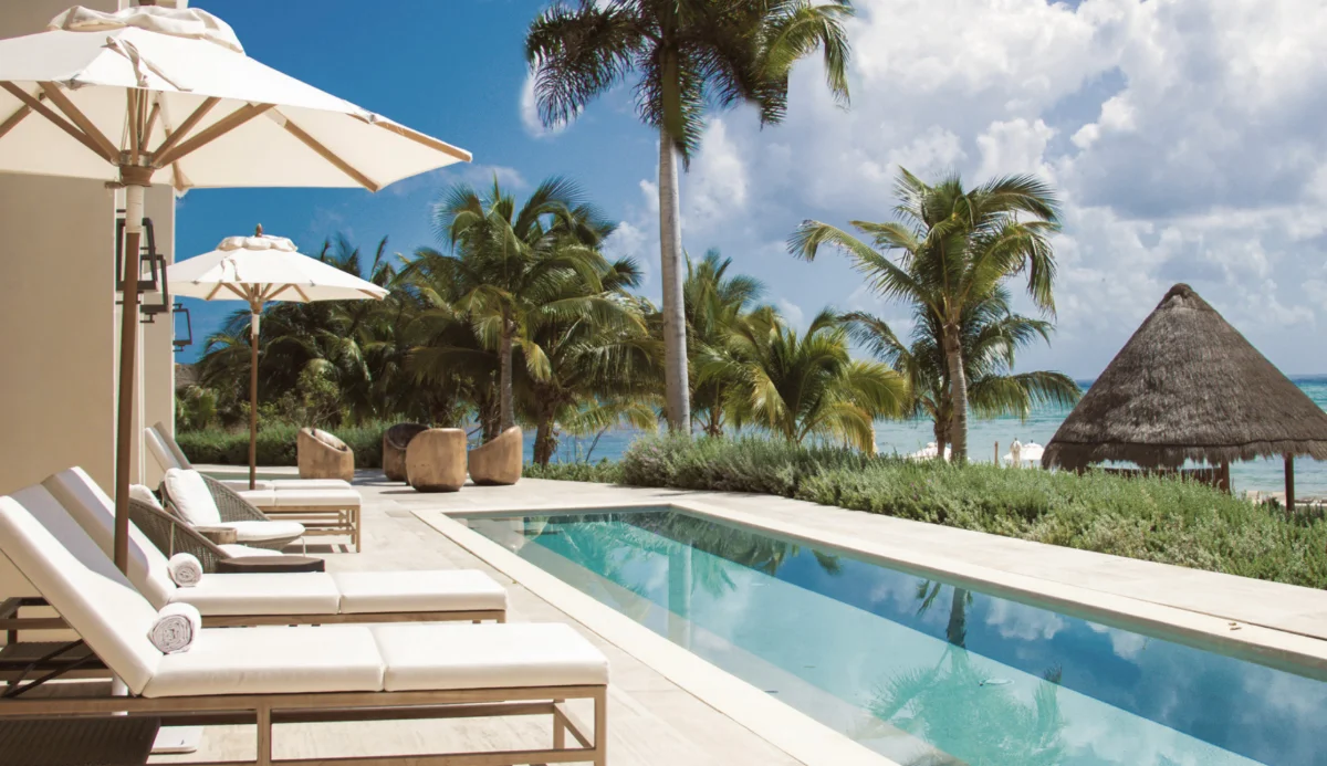 Costa Residences at Corasol seen from the water, beach loungers and palms along the sand