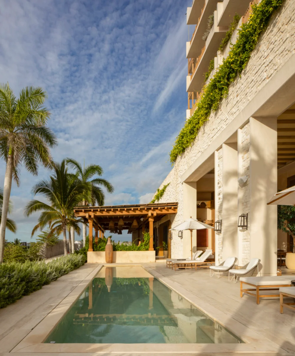 Lap pool and loungers on the terrace of Costa Residences at Corasol, planted stone facade above