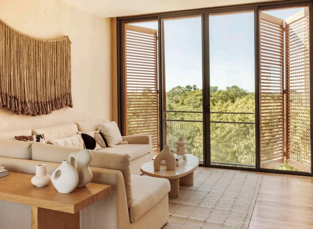 Living room of an apartment at The Village, Corasol, timber louvred doors open to the jungle canopy
