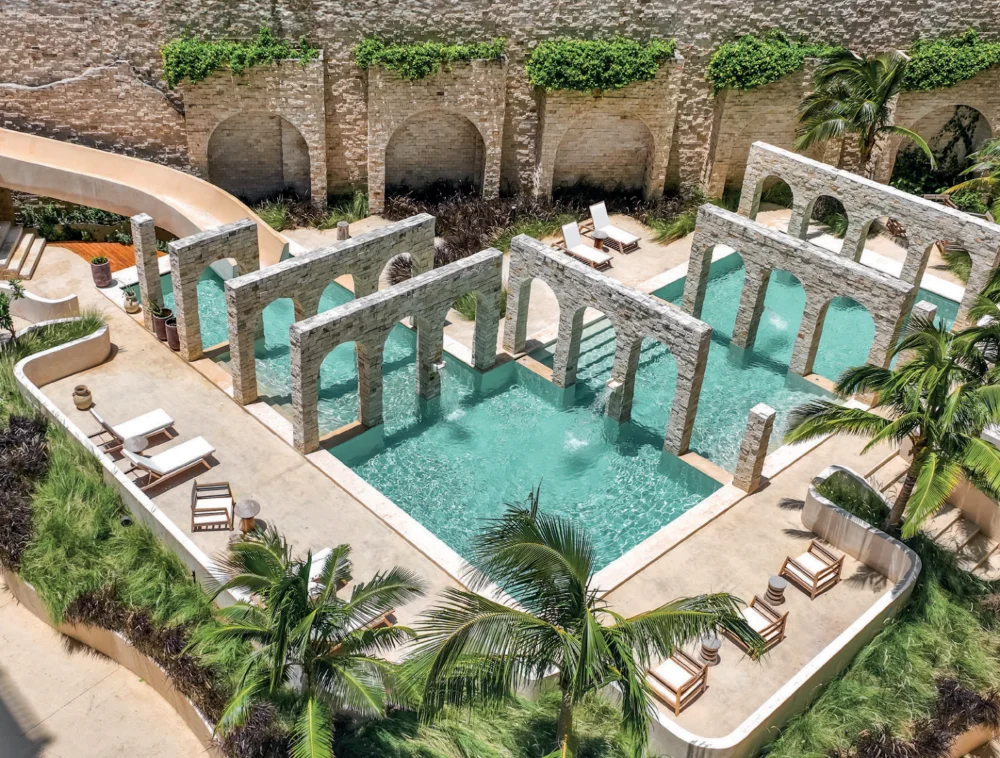 Stone arch pools and loungers in the Costa Residences amenity courtyard at Corasol