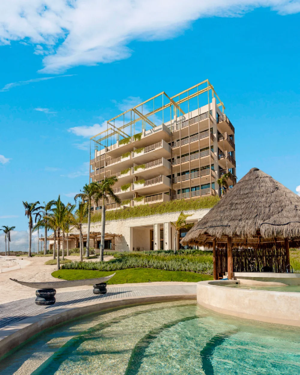 Costa Residences building at Corasol seen from the beach club pool, thatched palapa in the foreground