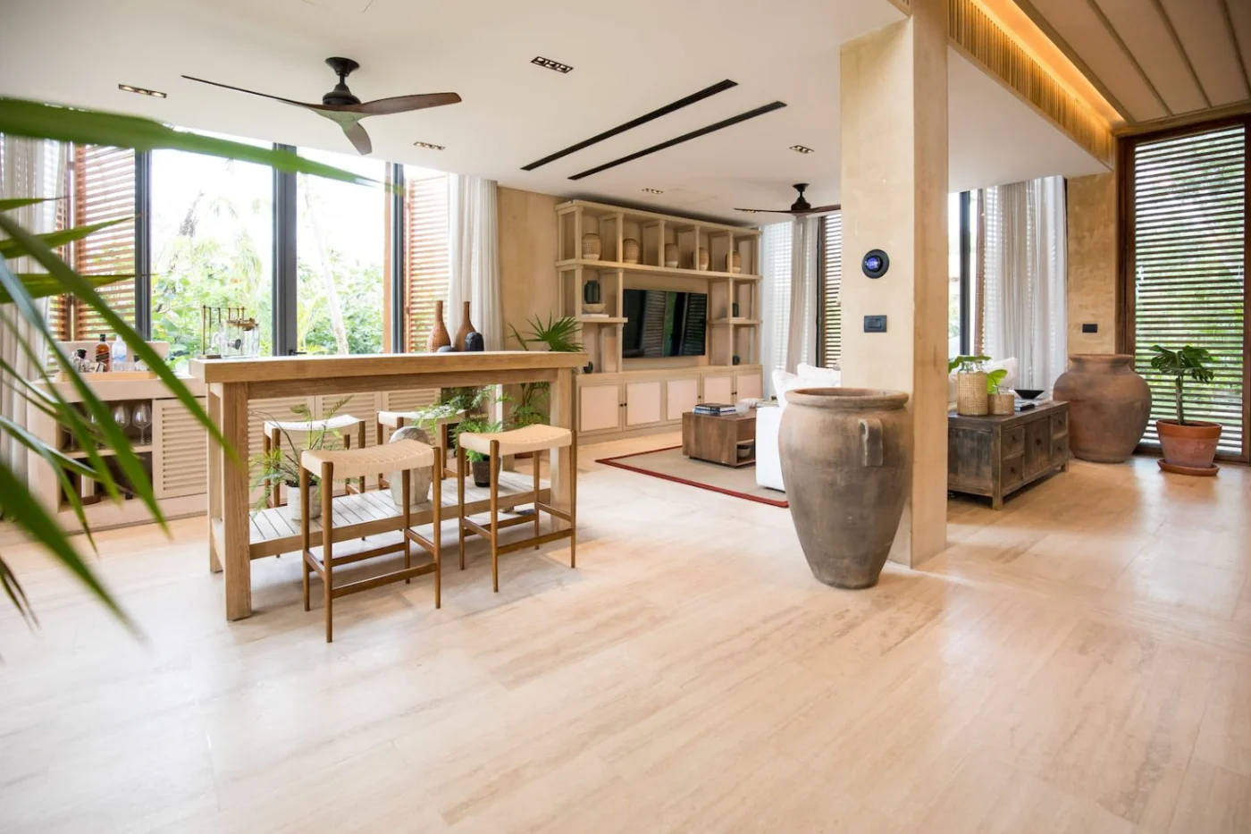 Covered outdoor living room of a Palm Villas estate home at Corasol, timber louvres folded open to the dining room