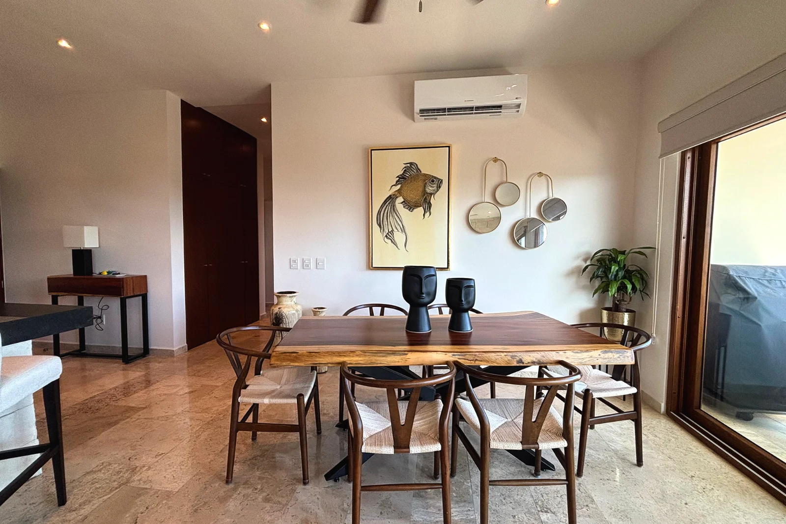 Comedor con mesa de madera de canto natural y pisos de mármol en un departamento de dos recámaras en Aldea Prestige, El Cielo Residencial