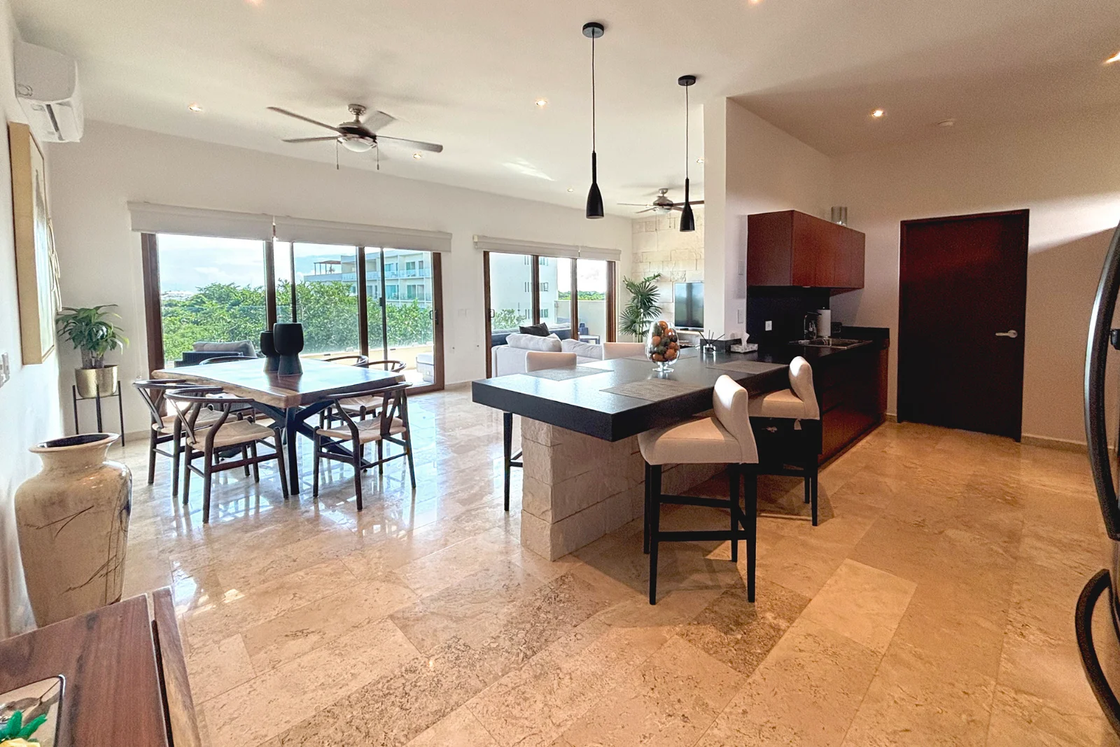 Cocina con isla de granito abierta al comedor y la sala en un departamento de dos recámaras en Aldea Prestige, El Cielo Residencial
