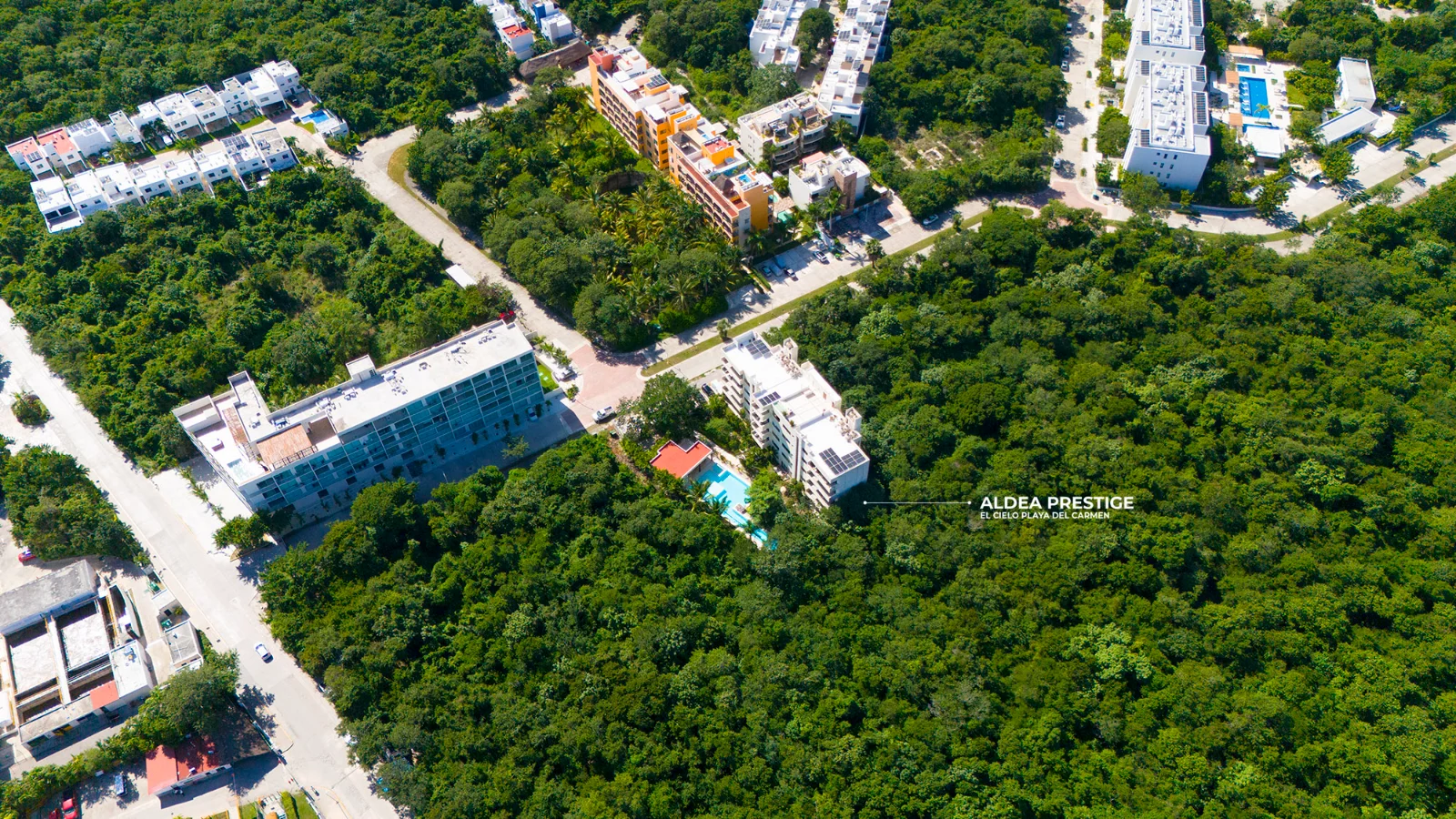 Vue aérienne des immeubles d'appartements dans El Cielo Residencial, rues en béton, piscines et jungle conservée autour