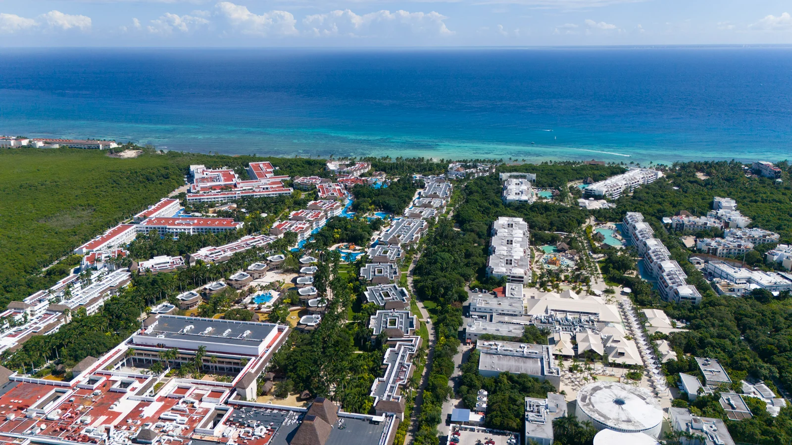 The Caribbean north of Playa del Carmen from the air, deep blue water over the reef and the Xcalacoco resorts along the sand, with El Cielo in the jungle behind