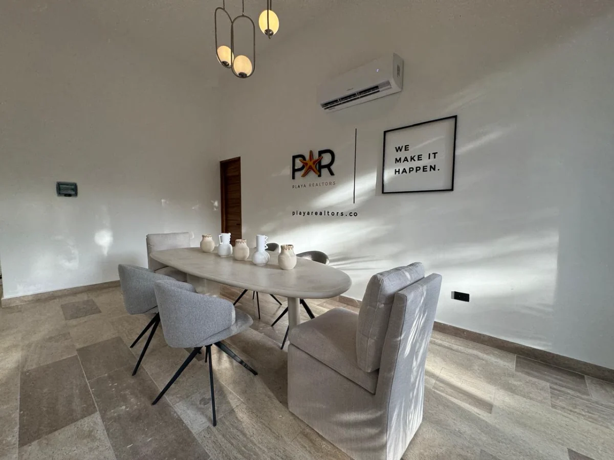 Salle de réunion du bureau Playa Realtors à Tulum, avec le logo et la phrase We Make It Happen au mur