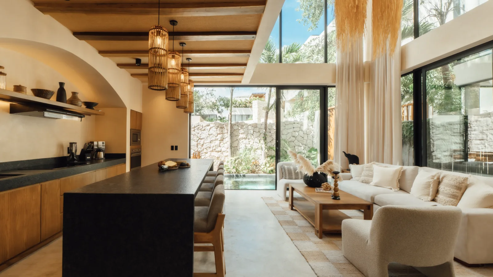 Bathroom of a Riviera Maya villa with a stone vanity, arched mirror and warm timber joinery