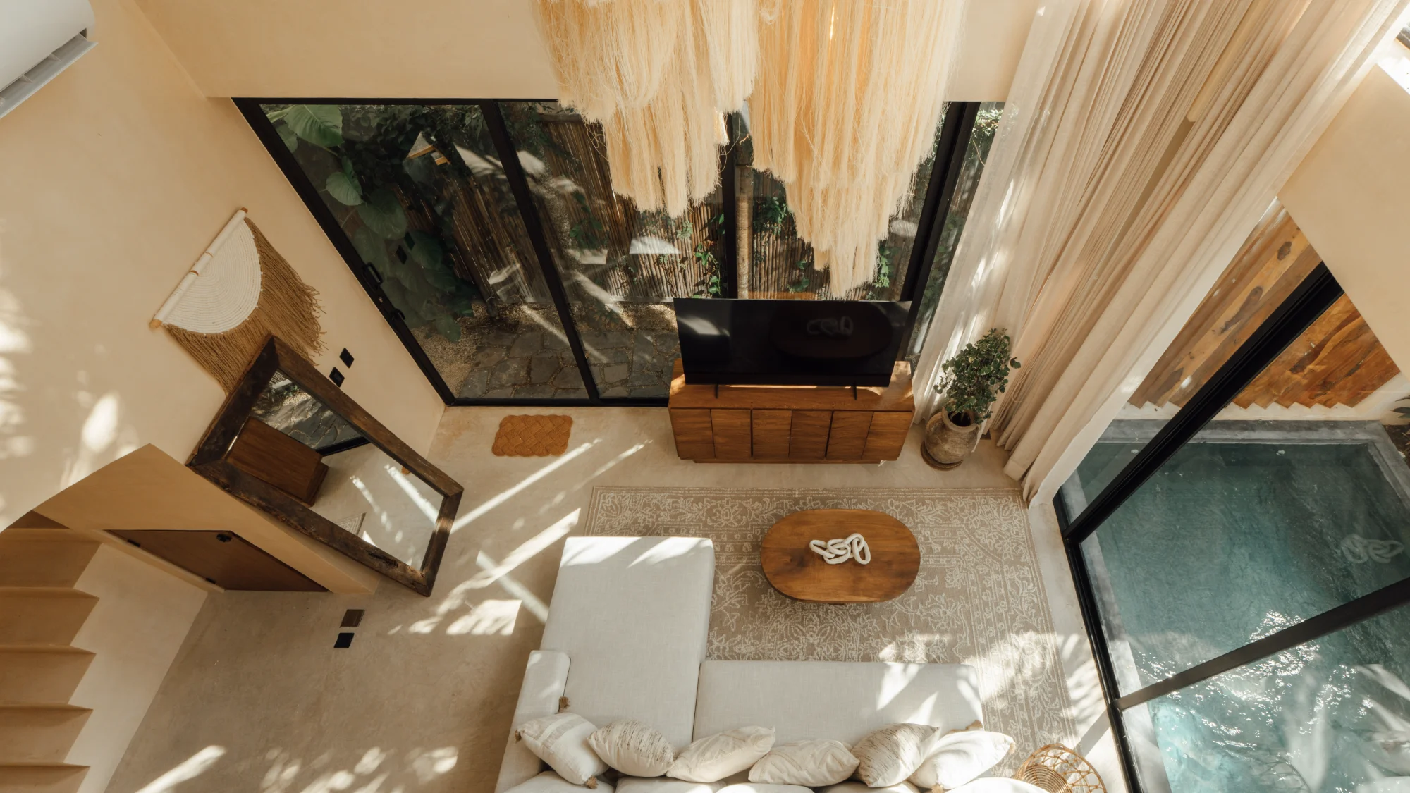 Overhead view of a Riviera Maya villa living room, linen sofa, macrame ceiling and a private plunge pool through the glass