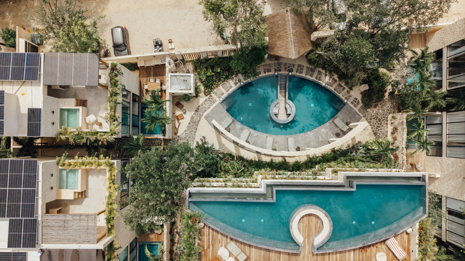 Aerial view of a Riviera Maya villa development, rooftop pools and jungle canopy around it