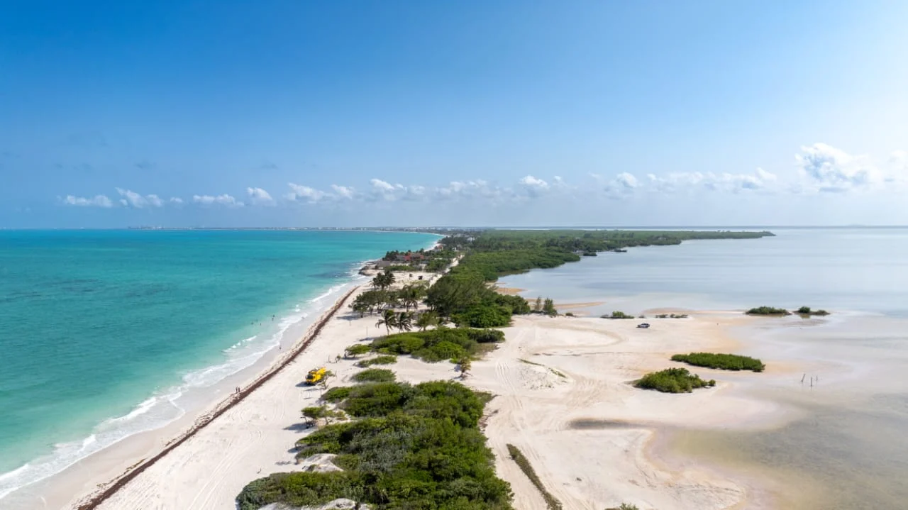 Vista aérea de la franja de Isla Blanca: el Caribe a la izquierda, la laguna Chacmuchuc y sus bancos de arena a la derecha, Cancún en el horizonte