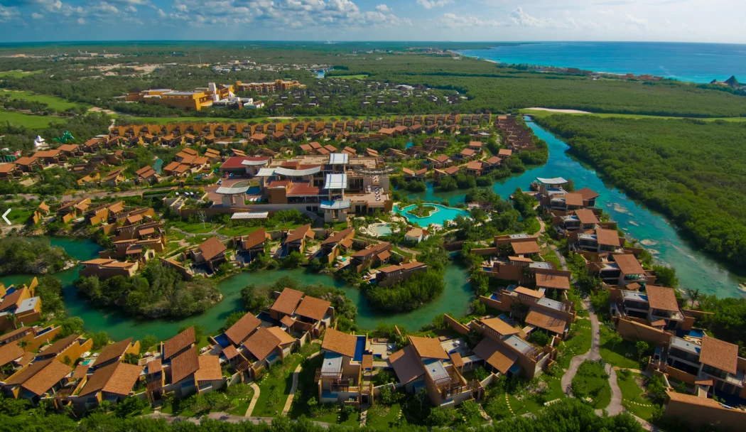 Oceanfront green and bunker at El Camaleón golf course at Mayakoba with palms and the turquoise Caribbean behind