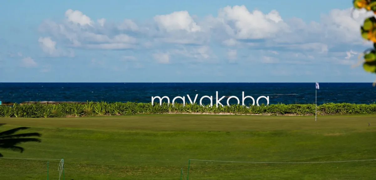 Green frente al mar en El Camaleón con las letras blancas de Mayakoba frente al azul profundo del Caribe
