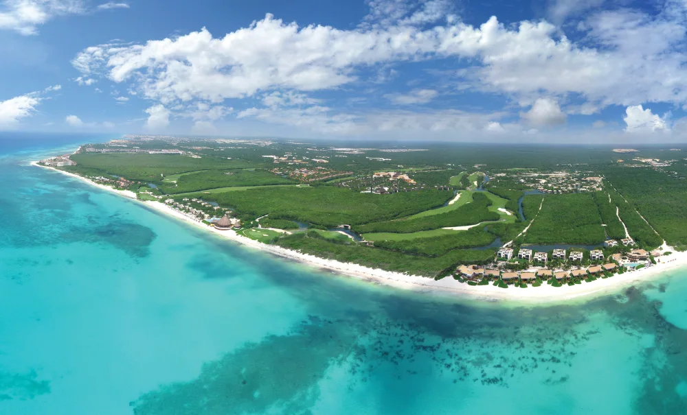 Vue aérienne des villas du resort Mayakoba aux toits de tuiles, entre canaux d'eau douce et mangrove, les Caraïbes derrière