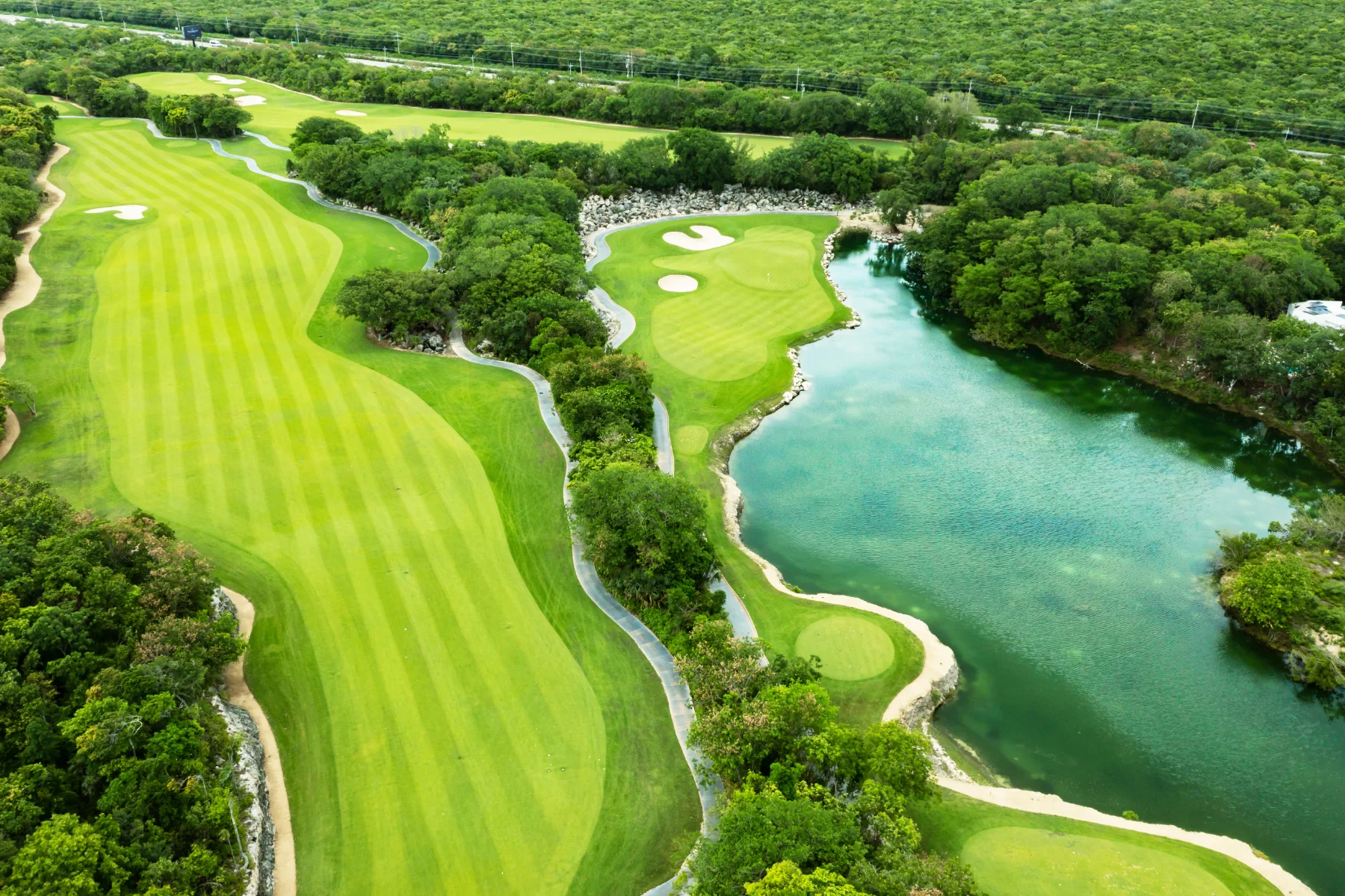 Aerial of the PGA Golf Academy Riviera Maya driving range at Tulum Country Club, covered bays and flags along the practice tee