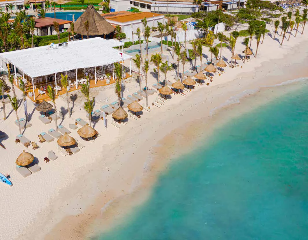 Vista aérea del Kay Beach Club en Tulum Country Club, palapas y camastros sobre arena blanca junto al Caribe turquesa