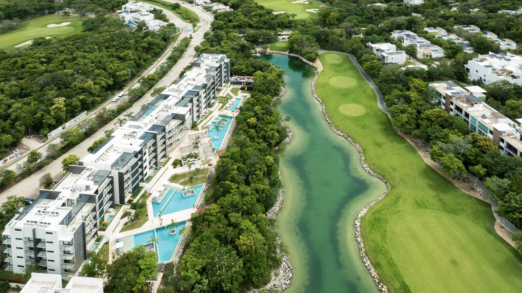 Vue aérienne des tours Kaan Ha à Tulum Country Club, piscines entre les bâtiments avec le lac et le parcours de golf à côté