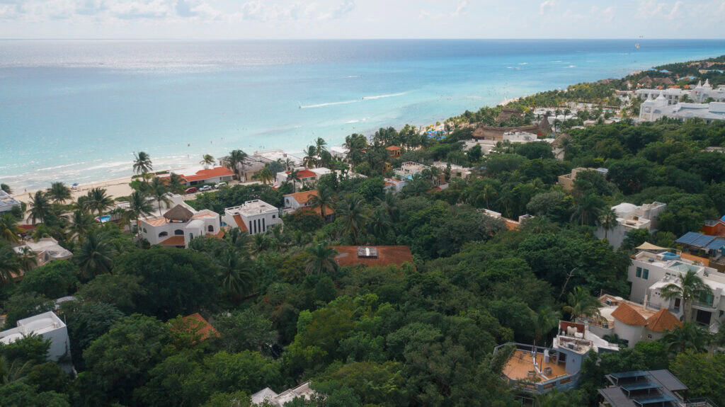 Beachfront view of Playacar Phase 1, Quintana Roo with lush greenery and upscale homes.